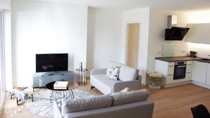 A modern living room with a grey sofa, a flat-screen TV, and a small coffee table. - Plenus Riverloft (Bremen)