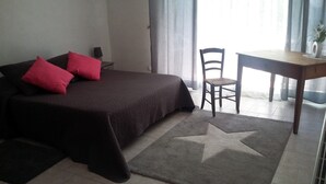 A bedroom with a bed, a chair, a desk, and a star-patterned rug. - le Temps des Cerises (Vinsobres)