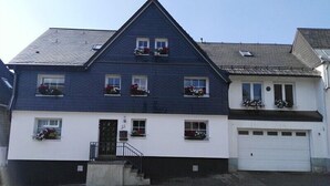 Una casa de dos pisos con fachada azul oscuro, sección inferior blanca y un garaje.