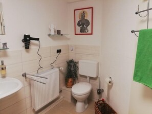 Ett badrum med ett element, toalett, handfat och en inramad tavla på väggen.