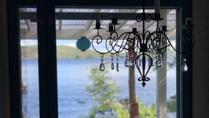 A chandelier with crystal decorations hanging in front of a window overlooking a body of water. - Little Finland (Jyväskylä)