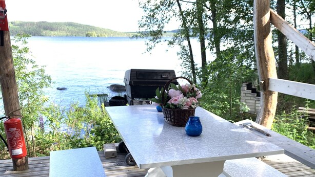 A wooden deck with a table and benches overlooking a lake. - Little Finland (Jyväskylä)
