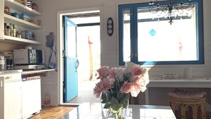 A kitchen with a white countertop, a vase of flowers, and a blue-framed window. - Little Finland (Jyväskylä)