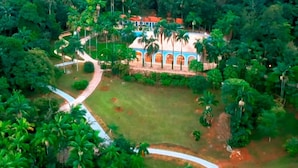 A tropical resort with a central building surrounded by lush greenery and palm trees. - Residencial Sênior Club Leger (São Paulo)