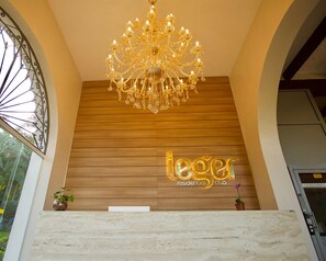 A chandelier, wooden panel wall, and a sign reading "leger residential club". - Residencial Sênior Club Leger (São Paulo)