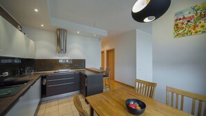 Eine moderne Küche mit einem Holztisch, einer schwarzen Fruchtschale und einem farbenfrohen Bild an der Wand.