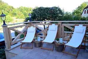 Una terraza de madera con cuatro sillas reclinables y dos faroles.