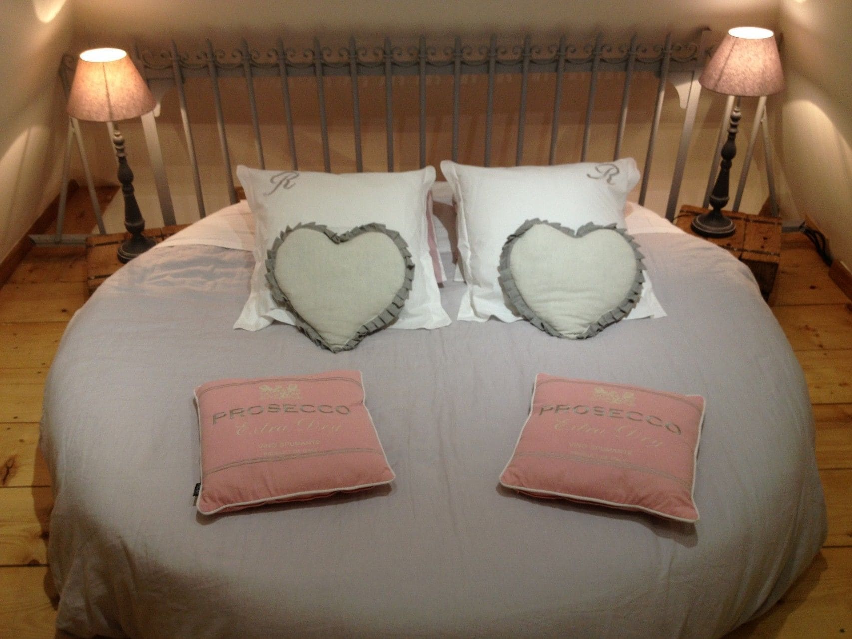 A bed with heart-shaped pillows and two pink pillows with text.