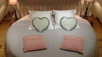 A bed with heart-shaped pillows and two pink pillows with text.