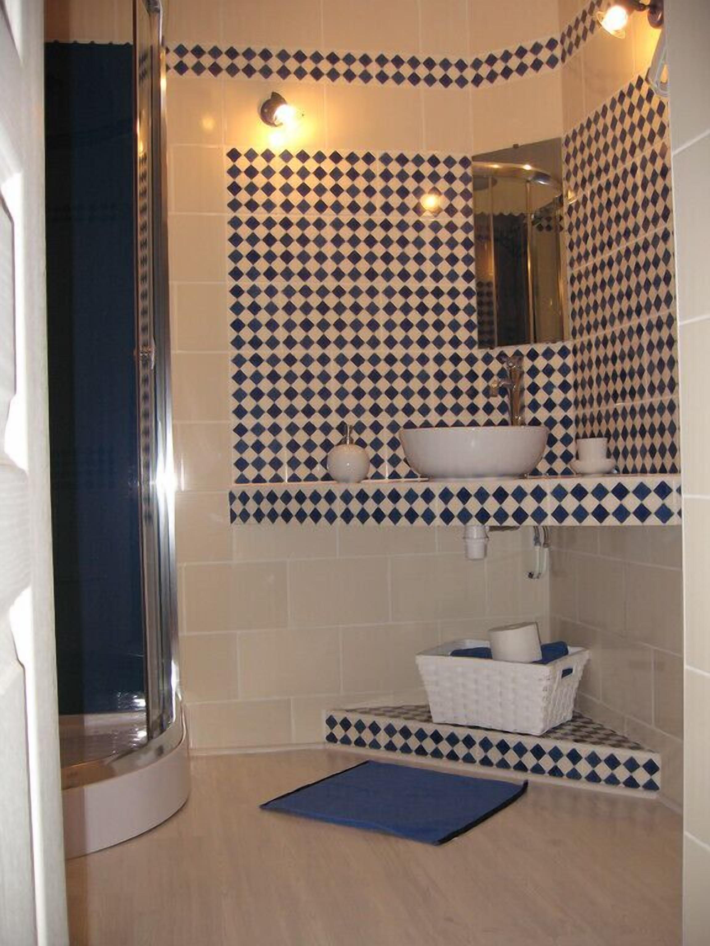 A bathroom with a patterned tile backsplash, a white sink, a mirror, and a shower enclosure.