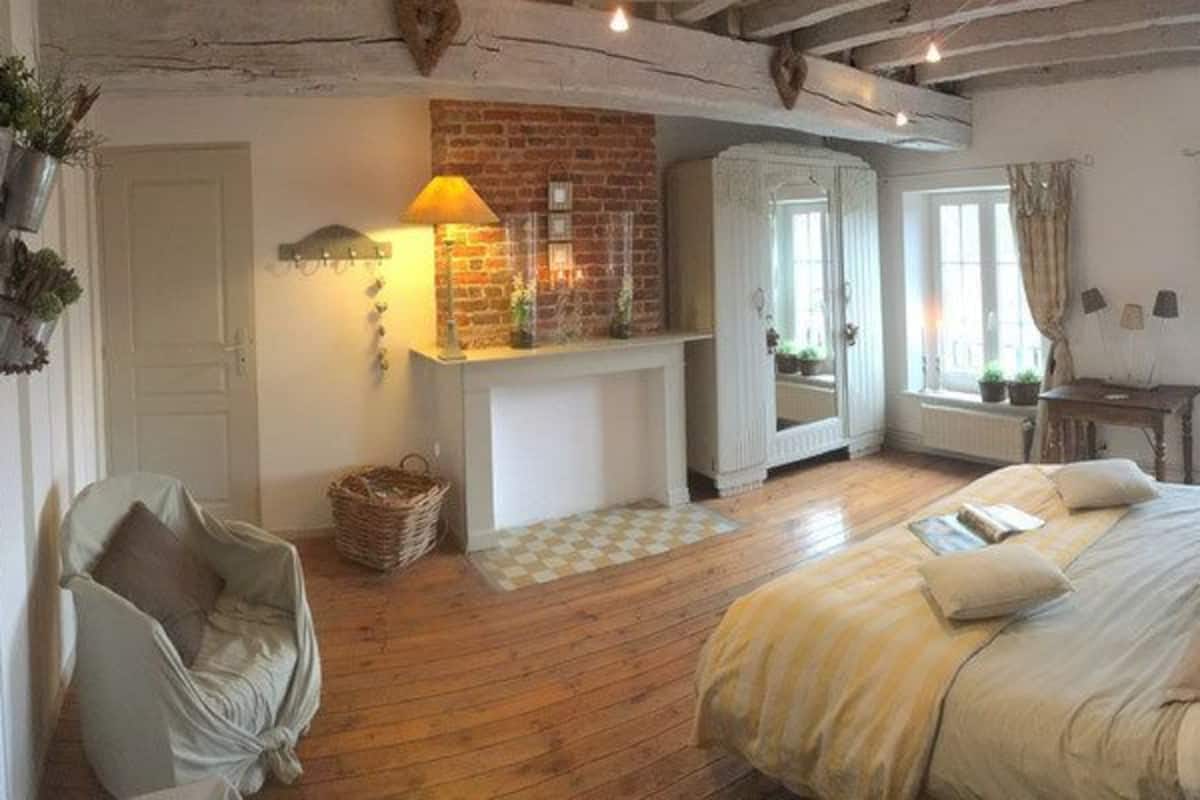 Ein gemütliches Schlafzimmer mit Bett, Stuhl, Kamin und Fenster.