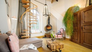 Un salón acogedor con una escalera de caracol, una estufa de leña y una planta colgante.