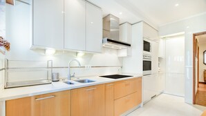 Een moderne keuken met witte kastjes, een roestvrijstalen afzuigkap en een dubbele spoelbak.