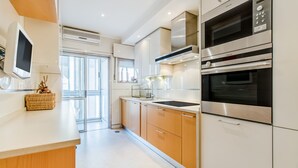 Een moderne keuken met roestvrijstalen apparatuur, een groot raam en een rieten mandje op het aanrecht.