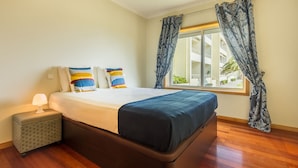 A neatly arranged bedroom with a large bed, a bedside table with a lamp, and a window with curtains. - São Félix Ocean Views Apartment (Vila Nova de Gaia)