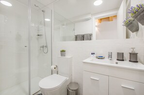 A modern bathroom with a glass-enclosed shower, a white toilet, and a vanity with a sink and storage.