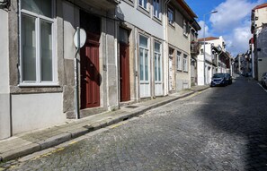 A narrow cobblestone street lined with historic buildings featuring large windows and red doors.