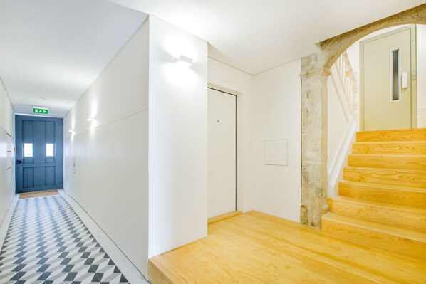 A hallway with a checkered floor leading to a wooden staircase. - Studio 183 (Porto)