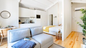 Um quarto moderno e bem iluminado, com sofá, cama, área de jantar e cozinha.