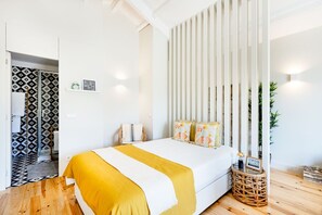 A modern bedroom with a bed, a decorative wall panel, a wicker side table, and a plant.
