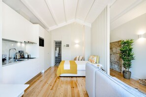 A modern kitchen with white cabinets, a stainless steel sink, and a wooden floor.