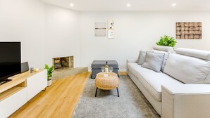 Ein modernes Wohnzimmer mit Flachbildfernseher, einer Couch, einem Couchtisch und einem Kamin.