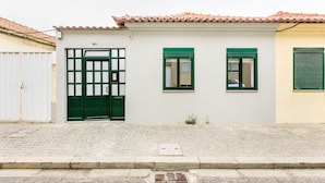 Ein Gebäude mit weißer Fassade, grünen Fensterrahmen und einem Ziegeldach.
