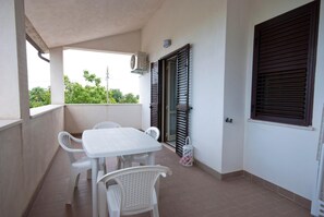 A balcony with a table and chairs, a window with shutters, and an air conditioning unit. - B&B Tra Gli Ulivi (Rocca San Giovanni)