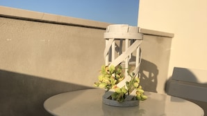 A small round table with a white metal frame, a white chair, and a potted plant with green and yellow flowers. - B&B Tra Gli Ulivi (Rocca San Giovanni)