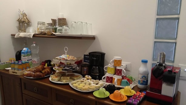 A breakfast buffet with various food items, beverages, and a coffee maker on a wooden counter. - B&B Tra Gli Ulivi (Rocca San Giovanni)