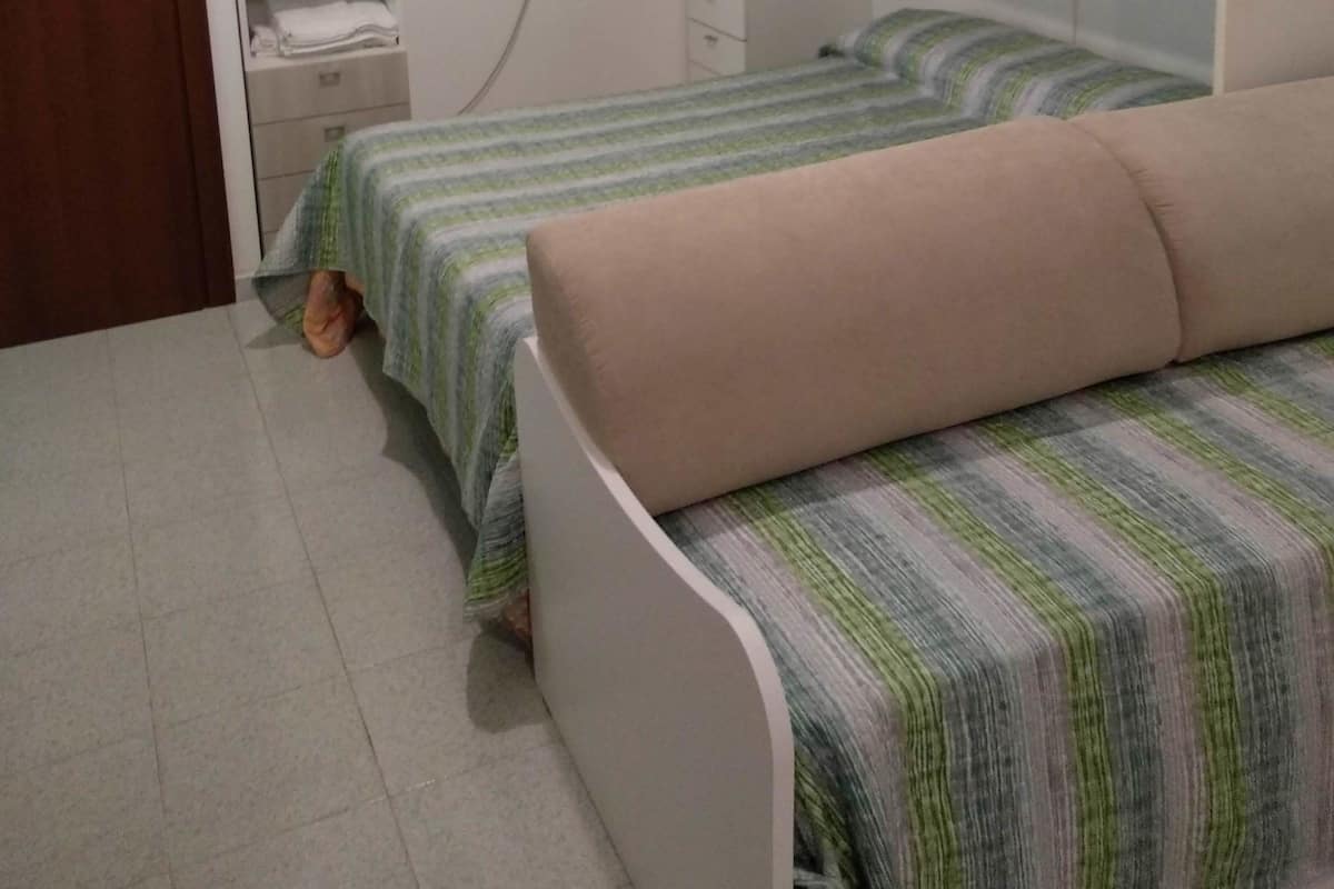A bedroom with a bed, a wardrobe, a bedside table, and a door.