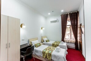 A hotel room with two beds, a desk, and a chair. There is an air conditioning unit on the wall and a window with curtains. - Hotel Suzani Samarkand (Samarkand)