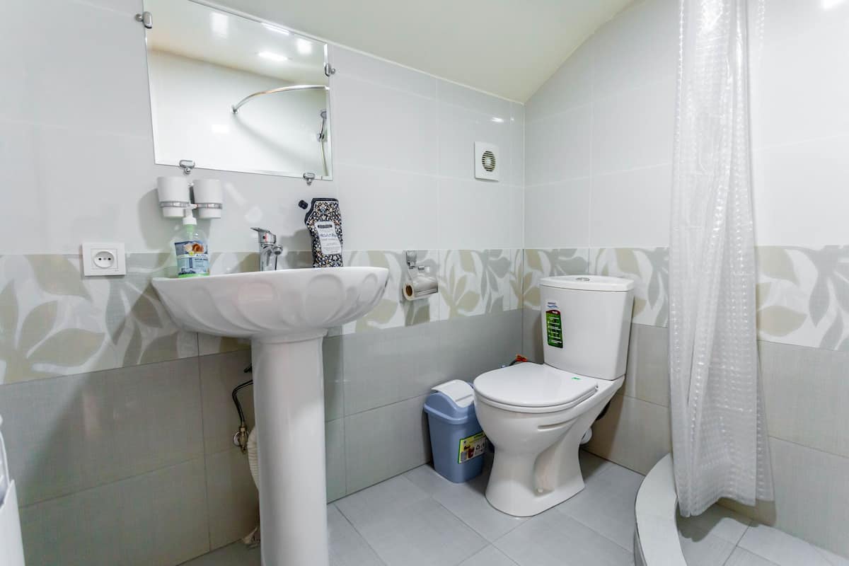 Un baño con lavamanos, inodoro y cortina de ducha blancos.