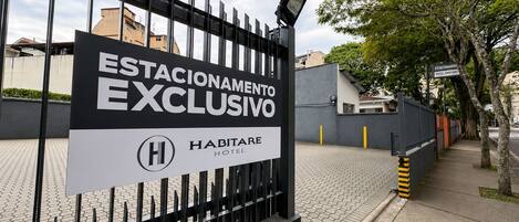 Puerta de entrada a un hotel con un cartel que dice 'ESTACIONAMIENTO EXCLUSIVO' y 'HABITARE HOTEL'.