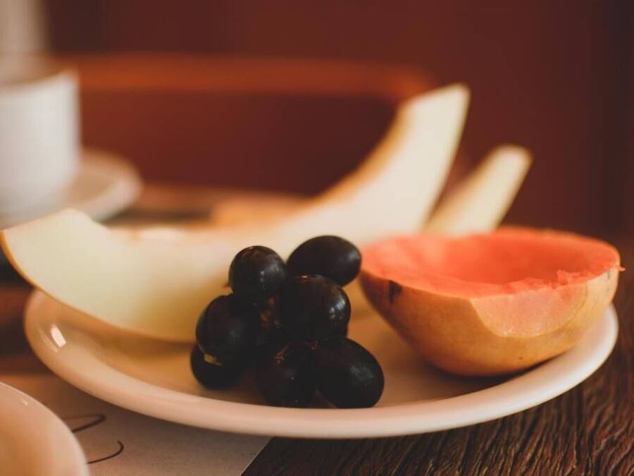 Een bord met gesneden fruit en druiven op een tafel.