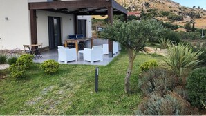 A modern house with a patio area, outdoor seating, and a mountain backdrop.