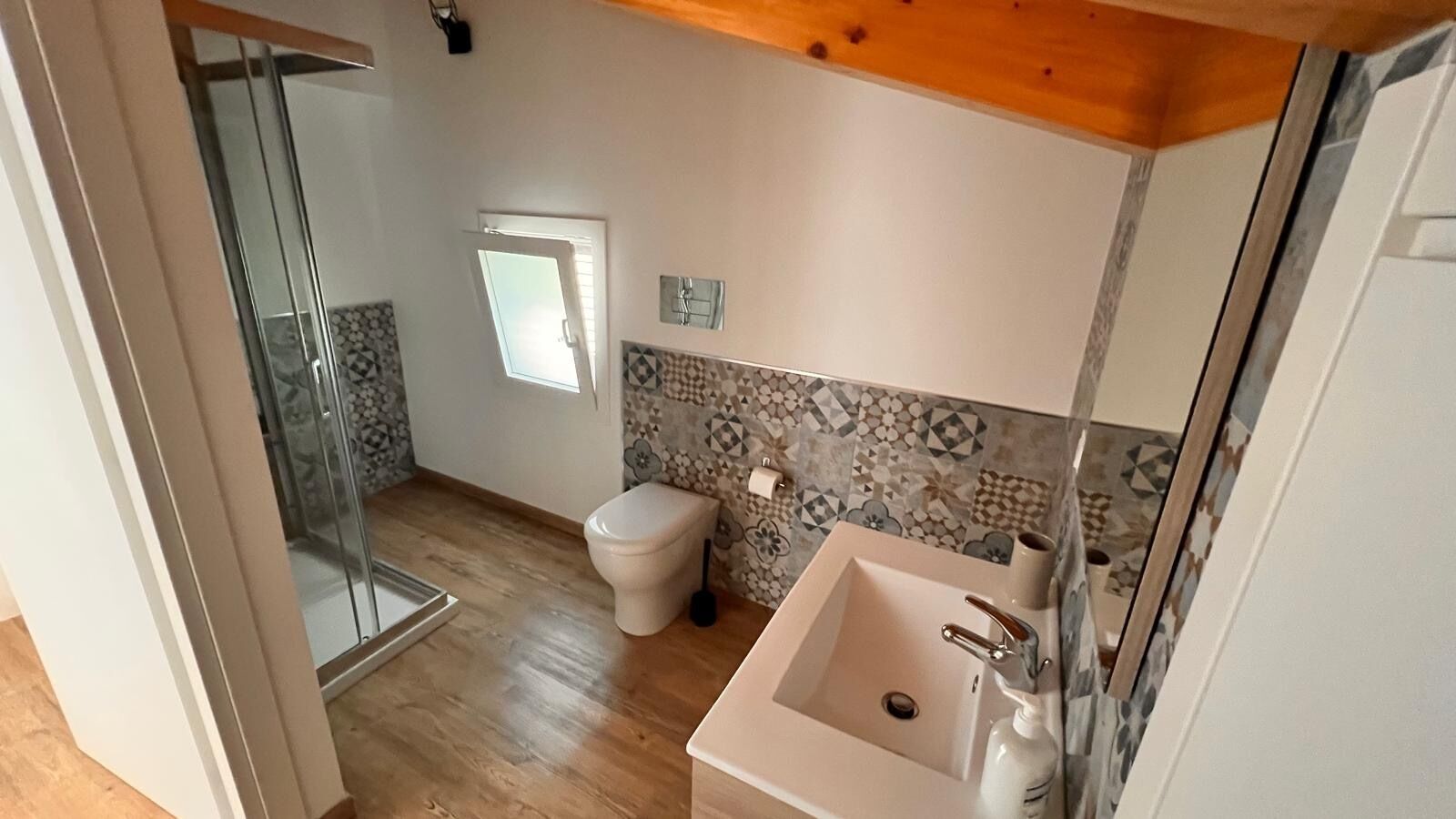 A bathroom with a shower, toilet, sink, and tiled backsplash.