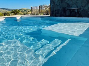 A clear pool with a stone wall and a wooden fence in the background. - Villa Minù, Scopello (scopello)