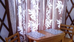 A wooden table with two chairs, a patterned curtain, and a lattice wall.