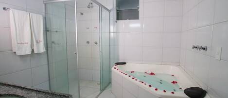 Ein modernes Badezimmer mit einer gläsernen Dusche, einer freistehenden Badewanne mit Rosenblättern und einem Waschtisch mit Granitplatte.