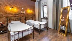 Ein Zimmer mit zwei Holzbett, einer Ziegelwand und einem großen Spiegel.