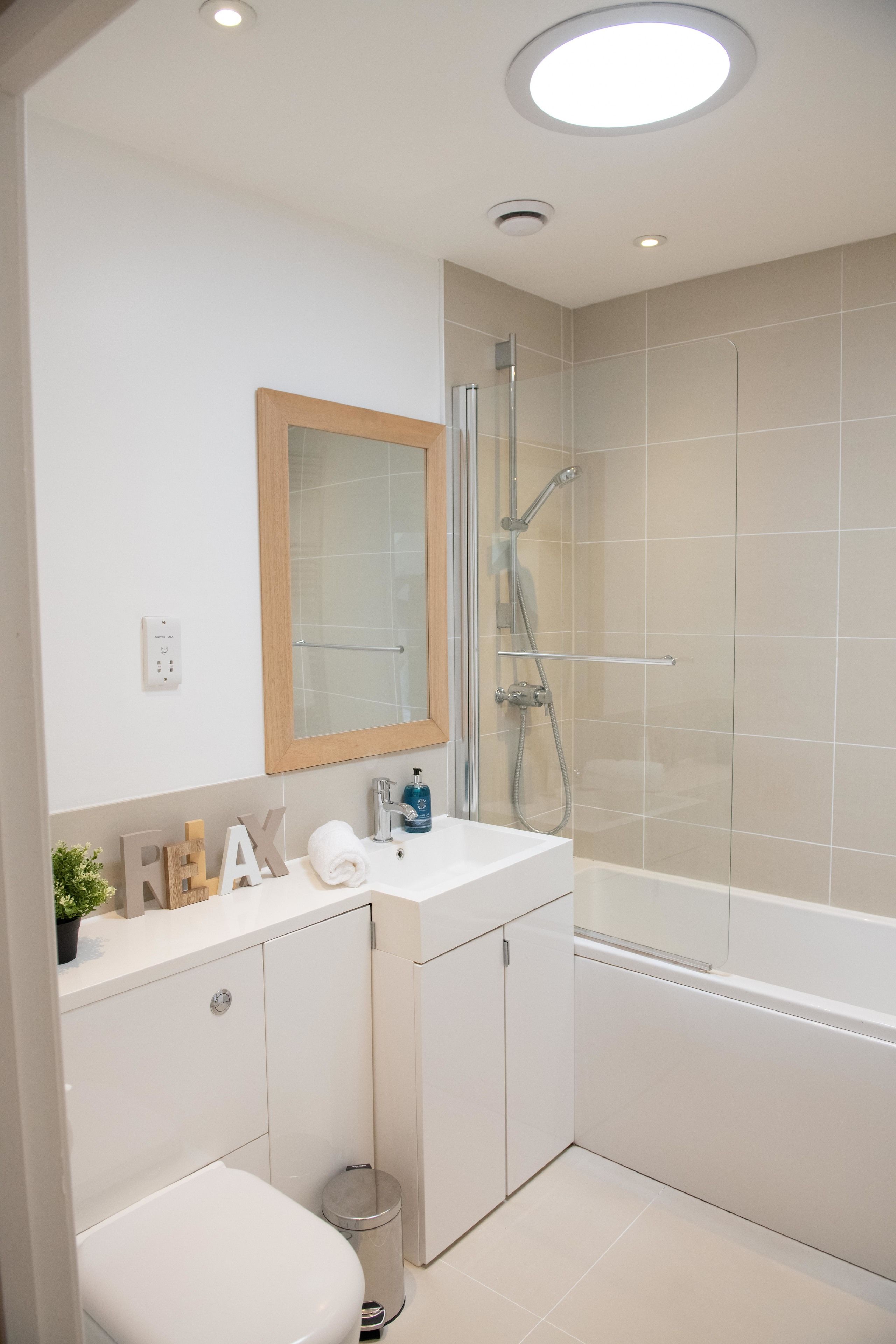 Ein modernes Badezimmer mit einem weißen Waschbecken, Spiegel und Dusche.