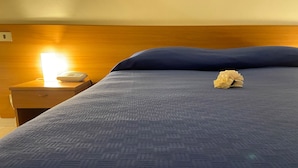 A neatly made bed with a blue textured bedspread and a single decorative item on the pillow. - Hotel Mercure (Castelluccio Inferiore)