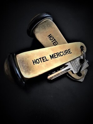 Two golden dumbbells with "HOTEL MERCURE" and "HOTEL" engraved on them, lying on a black surface. - Hotel Mercure (Castelluccio Inferiore)