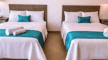 Deux lits jumeaux avec une literie blanche et turquoise, une tête de lit en bois et un seul oreiller blanc sur chaque lit.