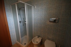 A bathroom with a glass-enclosed shower, a bidet, and a toilet.