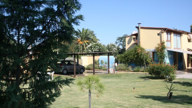 A residential area with a parked car, a small tree, and a building with a balcony. - Casa Anna (Quartu Sant'Elena)