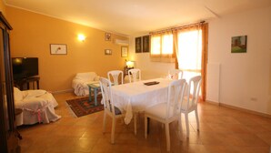 A living room with a dining area, a television, and a sofa. - Casa Anna (Quartu Sant'Elena)