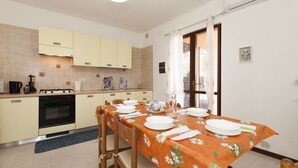 Una cocina moderna con una mesa de comedor para cuatro personas, horno empotrado y ventana con cortinas.