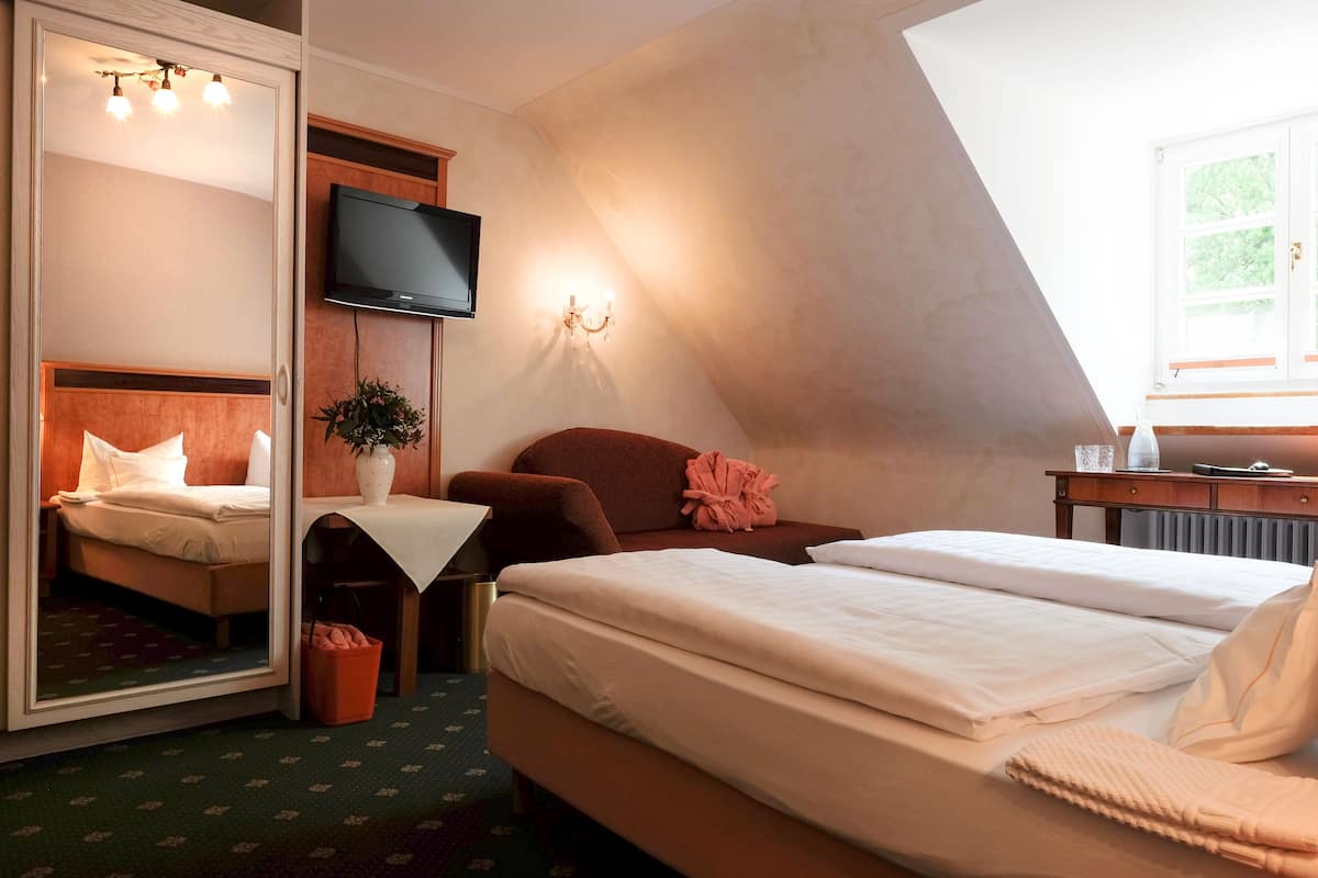 Une chambre d’hôtel avec un lit, un bureau, une chaise, une télévision et une fenêtre.